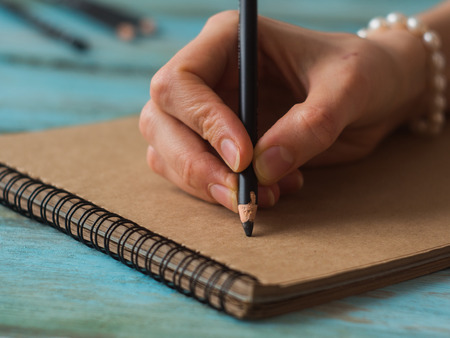 Close up of woman hands writing at cafe.