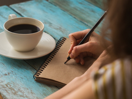 Close up top view of writing woman drinking coffee.の写真素材