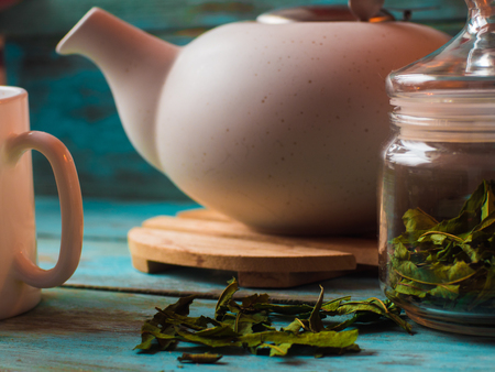 Tea concept, cup with teapot decorated with green leaf teaの写真素材