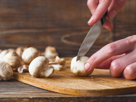 Woman hands slices mushrooms in kitchen. Female making mushroom sauce.の写真素材