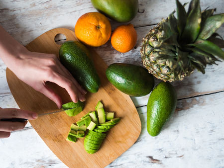 female hands cooking with avocado at table in home kitchen