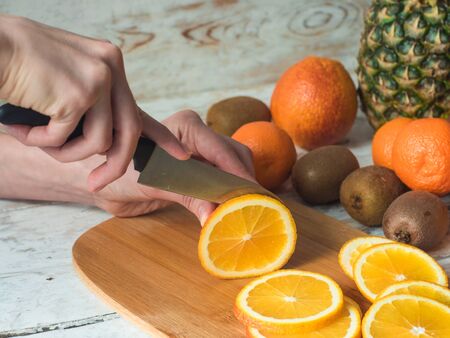 Close up Woman hands slicing orange on chopping boardの写真素材