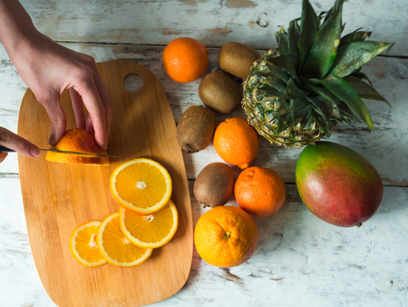 Top view of woman hands cutting fresh oranges with knife.の写真素材
