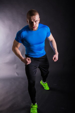 Full length portrait of a muscular man in sports wear standing on a dark backgroundの写真素材
