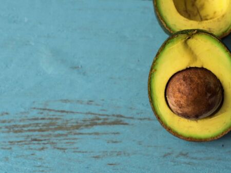 Fresh organic avocado on blue old wooden table, top view with copy space.