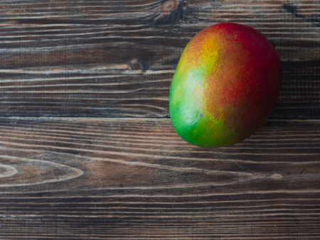 Ripe mango fruit lying over the dark colored wooden board. Space for text.の写真素材