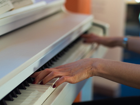 Close up of the hands of a young woman playing piano.の写真素材