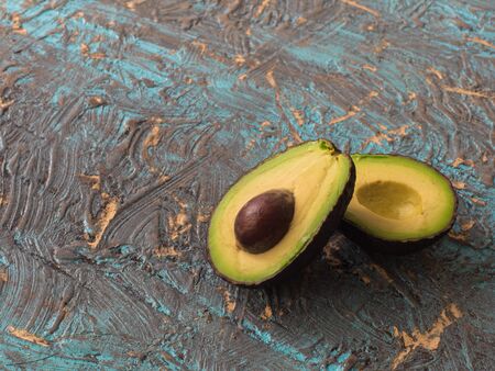 Fresh avocado slices on dark blue background, side view.