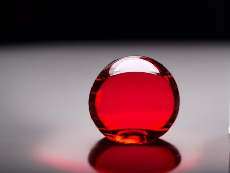 Red glass sphere on a black background with reflection. Shallow depth of fieldの素材