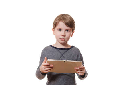Portrait of a cute European boy hold tablet computer and looking confidently at camera on white...
