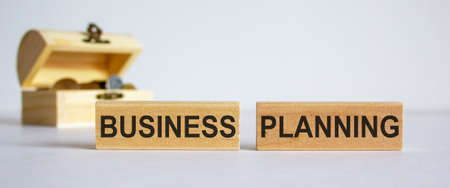 Concept words business planning on blocks on a beautiful white background, small chest with coins.の写真素材