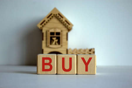 Cubes form the word 'buy' in front of a miniature house.の写真素材