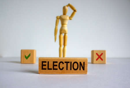 Election word written in wooden block. Wooden model of a man reflecting on a choice.の写真素材