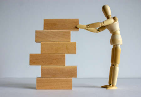 Concept of building success foundation. Wooden model of human put wooden blocks on the stack of wooden blocks.の写真素材