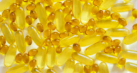 Yellow vitamins tablets, fish oil, Omega Vitamin E. Pills on a white background. Web banner. Beautiful background. Blurred image.の写真素材