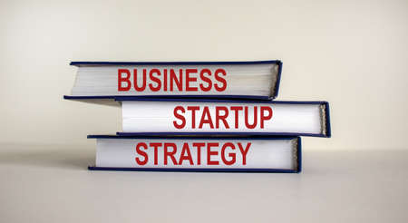 Books with text 'strategy startup business' on beautiful white background. Business concept. Copy space.の写真素材