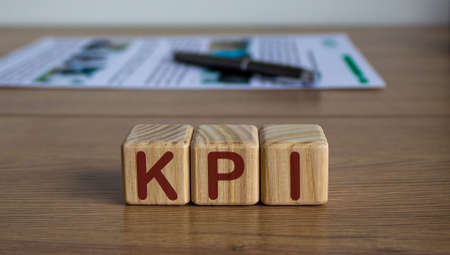 Concept word KPI on cubes on a beautiful wooden table, pen and documents.