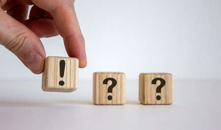 Male hand putting dice with exclamation mark near dice with question marks.の写真素材