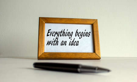 Wooden picture frame with inscription 'everything begins with an idea' on beautiful white background. Pen on the table. Concept.の写真素材