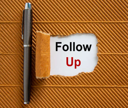 The text 'folloe up' appearing behind torn brown paper. Beautiful metalic pen.の写真素材