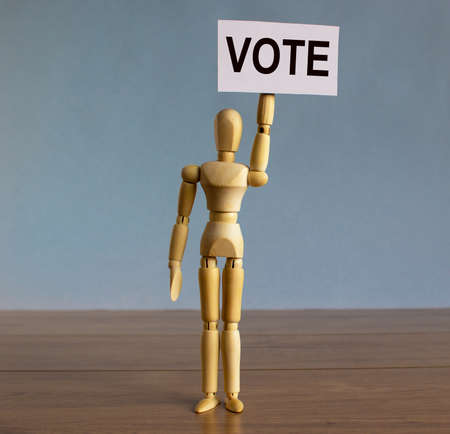 Wooden model of a man holding a tablet saying 'vote'.の写真素材