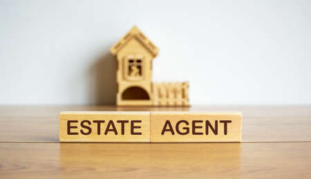 Blocks form the words 'estate agent' in front of a miniature house.の写真素材