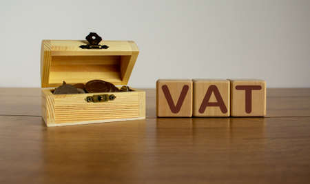 Concept word vat on cubes on a beautiful wooden table, small chest with coins.の写真素材