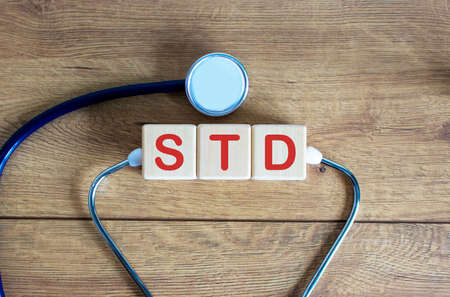 COVID-19 Pandemic Coronavirus concept. Wooden cubes with the inscription STD and stethoscope.の写真素材