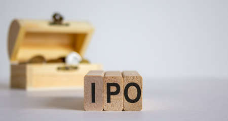 Concept word 'ipo' on wooden blocks on a beautiful white background, small chest with coins.の写真素材
