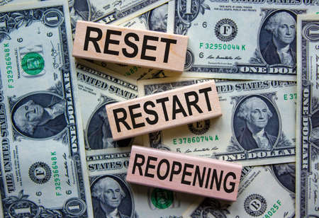 Concept words 'reset, restart, reopening' on wooden blocks on a beautiful background from dollar bills.の写真素材