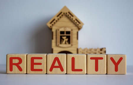 Cubes form the word realty in front of a miniature house.の写真素材
