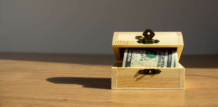 Concept image for your text. Beautiful wooden table, small chest with dollar bills.の写真素材