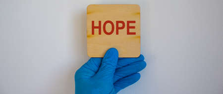 COVID-19 Pandemic Coronavirus concept.The doctor holds in his hand a tablet saying hope. Gloved hand.の写真素材