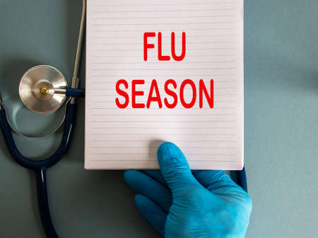 Hand in blue glove, white card with words 'flu season' and stethoscope.の写真素材