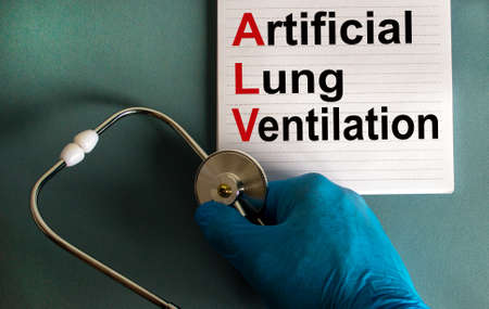 Hand in blue glove with stethoscope, white card with words 'artifical lung ventilation'.の写真素材