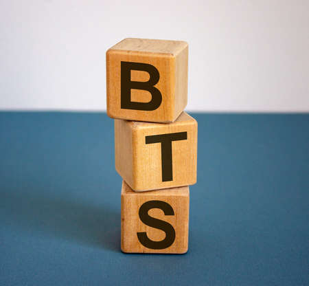 Wooden cubes with the inscription 'BTS'. Beautiful blue table and white background, copy space.の写真素材