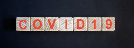 World pandemic virus COVID 19 word on wooden blocks with dark blue backgroundの写真素材