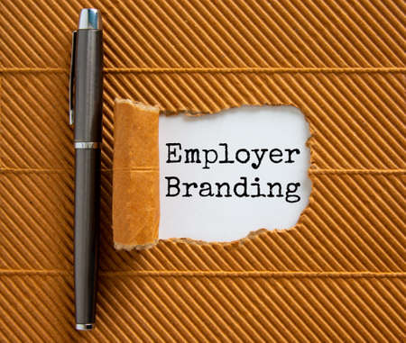 The text 'employer branding' appearing behind torn brown paper. Beautiful metalic pen.の写真素材
