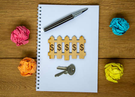 White note on beautiful wooden table, metalic pen, keys, colored paper and miniature wooden fence...