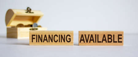Concept words 'financing available' on blocks on a beautiful white background, small chest with coins.の写真素材