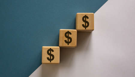 Wood cubes with dollar sign stacking as step stair on paper blue and white background, copy space. Business concept success process.の写真素材