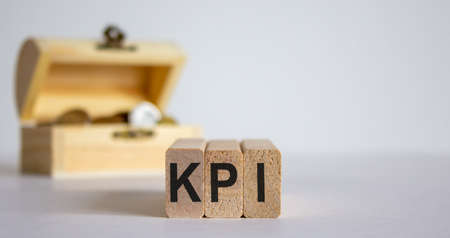 Concept word KPI on cubes on a beautiful white background, small chest with coins.の写真素材