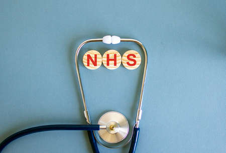COVID-19 Pandemic Coronavirus concept. Wooden circles with the inscription NHS and stethoscope.の写真素材