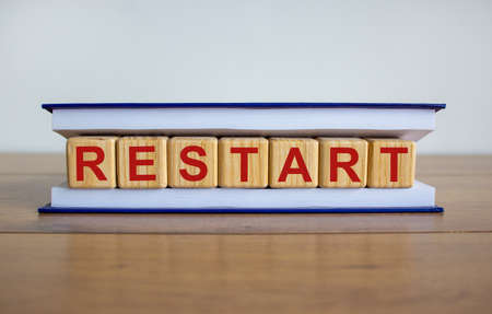 Concept word 'restart' on cubes between pages of a book on a beautiful wooden table. White background. Business concept.の写真素材