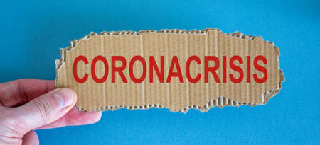 COVID-19 Pandemic Coronavirus concept. Word coronacrisis on the piece of cardboard between fingers.の写真素材