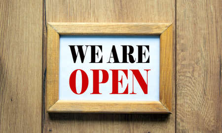 Wooden picture frame with inscription 'we are open' on beautiful wooden background. Concept.の写真素材