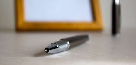 Notebook and pen on beautiful white fon. Wooden picture frame and cap in the background.の写真素材