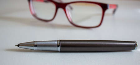 Metal pen and beautiful glasses on a white table. Business concept.の写真素材