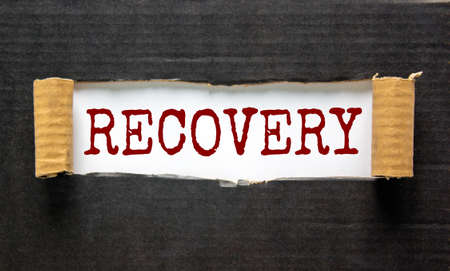 The word 'recovery' appearing behind torn black paper. Beautiful background. Business concept.の写真素材