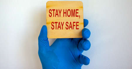 COVID-19 Pandemic Coronavirus concept.The doctor holds in his hand a tablet saying stay home, stay safe. Gloved hand.の写真素材